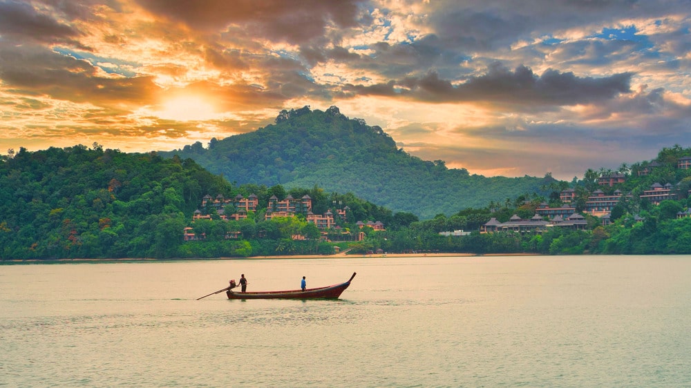 Kleines Boot auf dem Meer bei Sonnenuntergang in Thailand; mit mobilem Internet verbunden bleiben