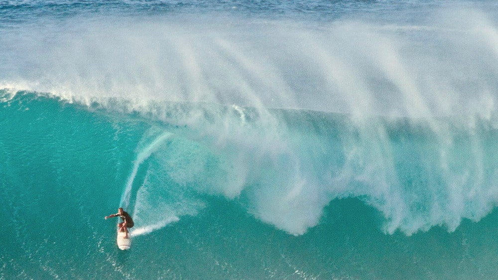 Surfeur chevauchant une énorme vague en Australie ; restez connecté avec une eSIM pendant vos voyages