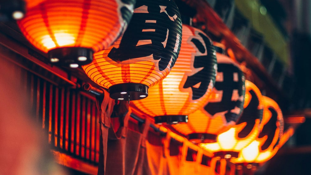Rijen rode Japanse lantaarns verlichten de straat in de avond; blijf online met eSIM in Japan
