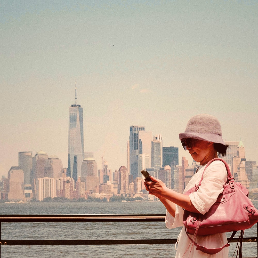 Toerist met smartphone voor skyline van New York met mobiel internet via Amerikaanse eSIM