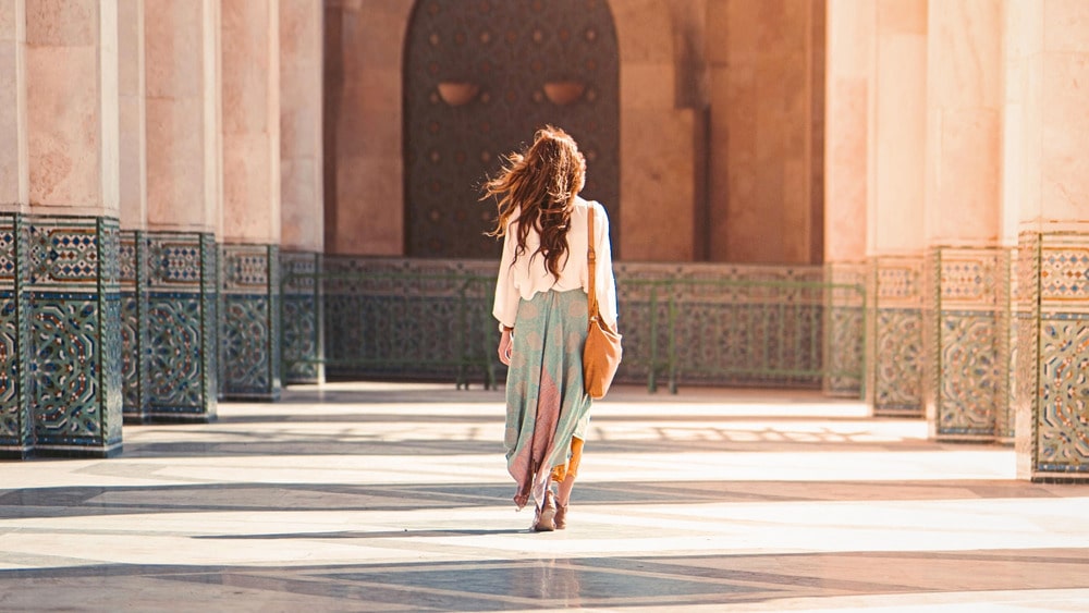 Vrouw bij de Hassan II-moskee in Casablanca; symbool van moderne connectiviteit en cultuur in Marokko