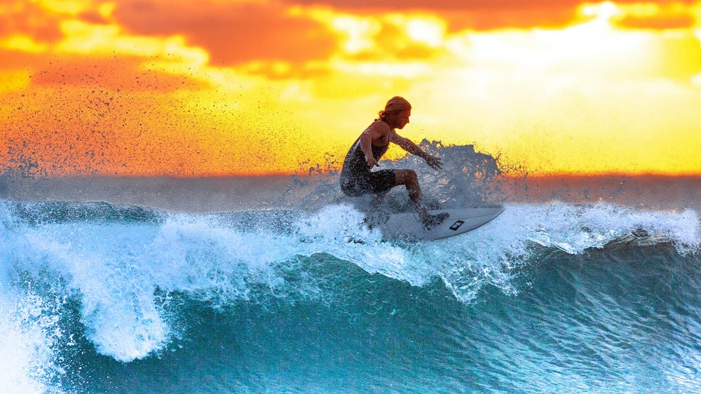 Surfer in Curaçao at sunset; stay online with your local SIM card while traveling